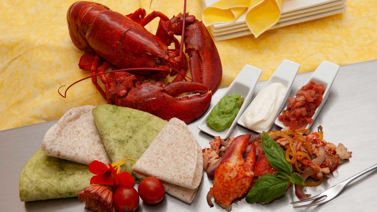 lobster fajita ingredients sit next to a fully cooked lobster