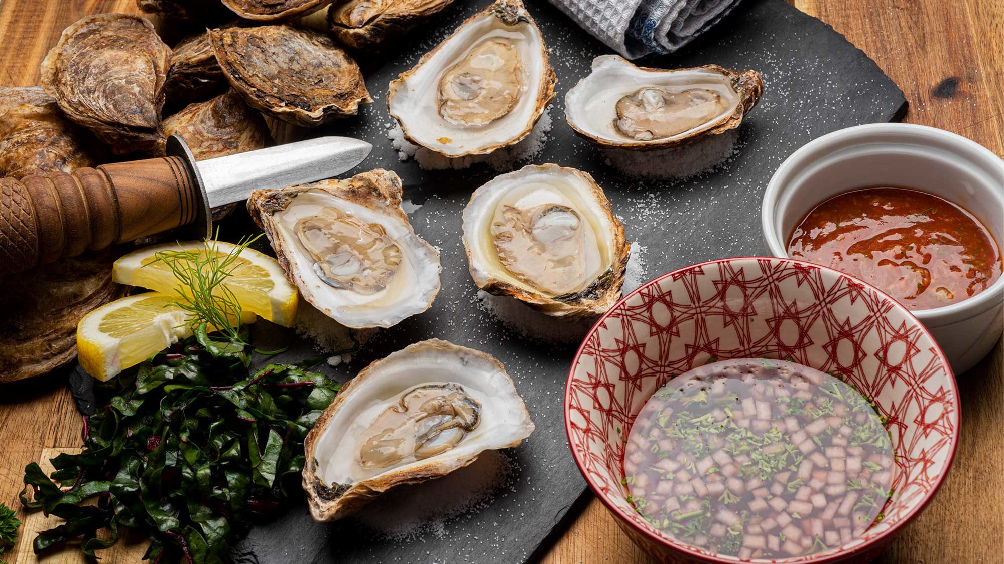 half shell raw oysters sits next to a small bowl of prepared cocktail sauce